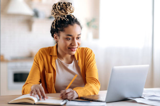 A woman sitting at a table with a laptop and notebook.